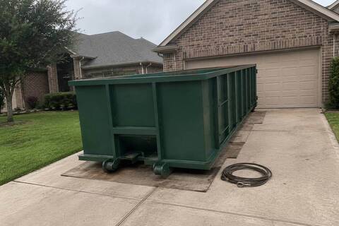 Roll-off container set on boards on a residential driveway