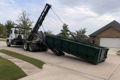 Roll-off truck lowering a container onto a residential street