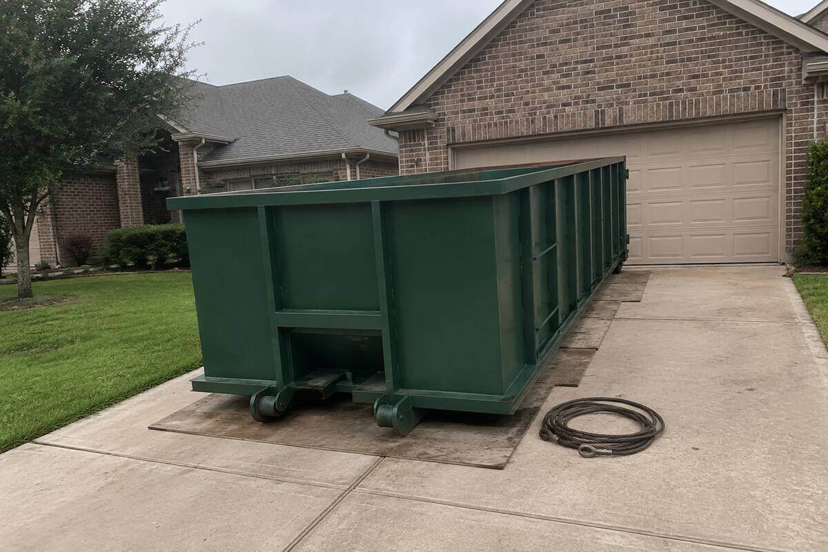 Roll-off container set on boards on a residential driveway